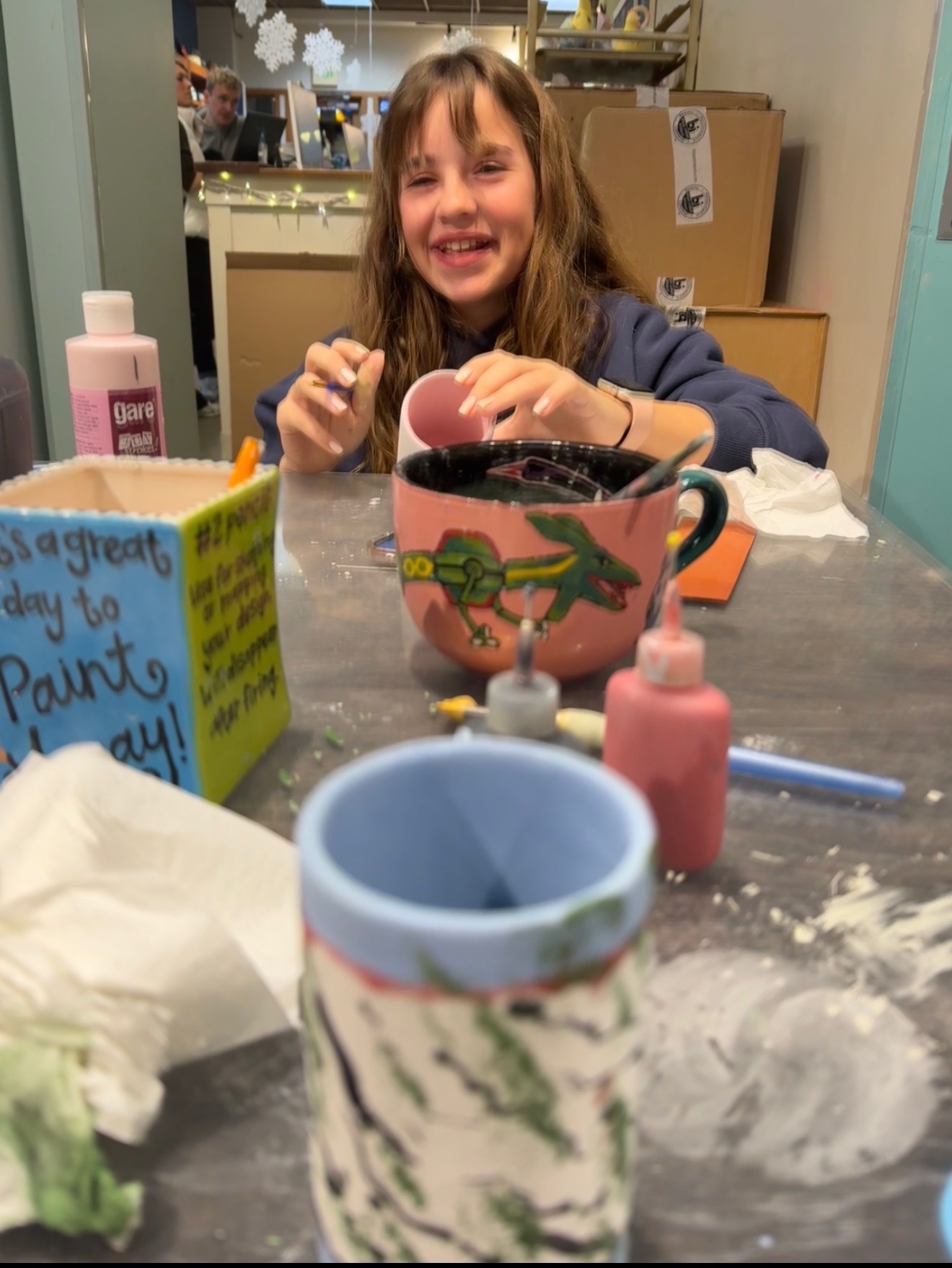 The artist smiling while hand-painting pottery in the studio